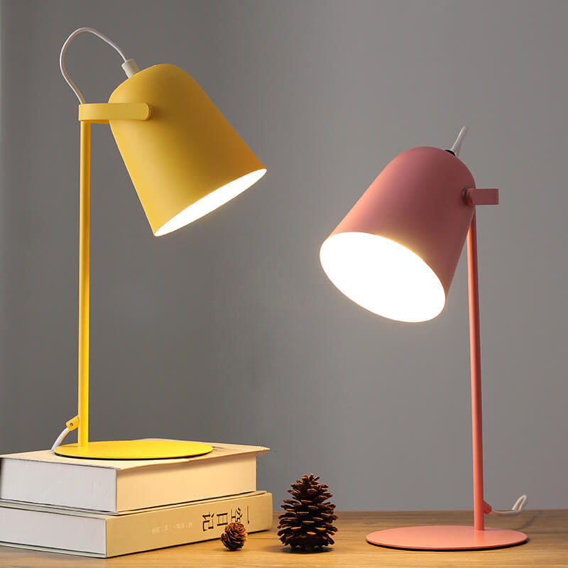 Yellow and pink versions of the lamp lit side by side, with books and a pine cone 5