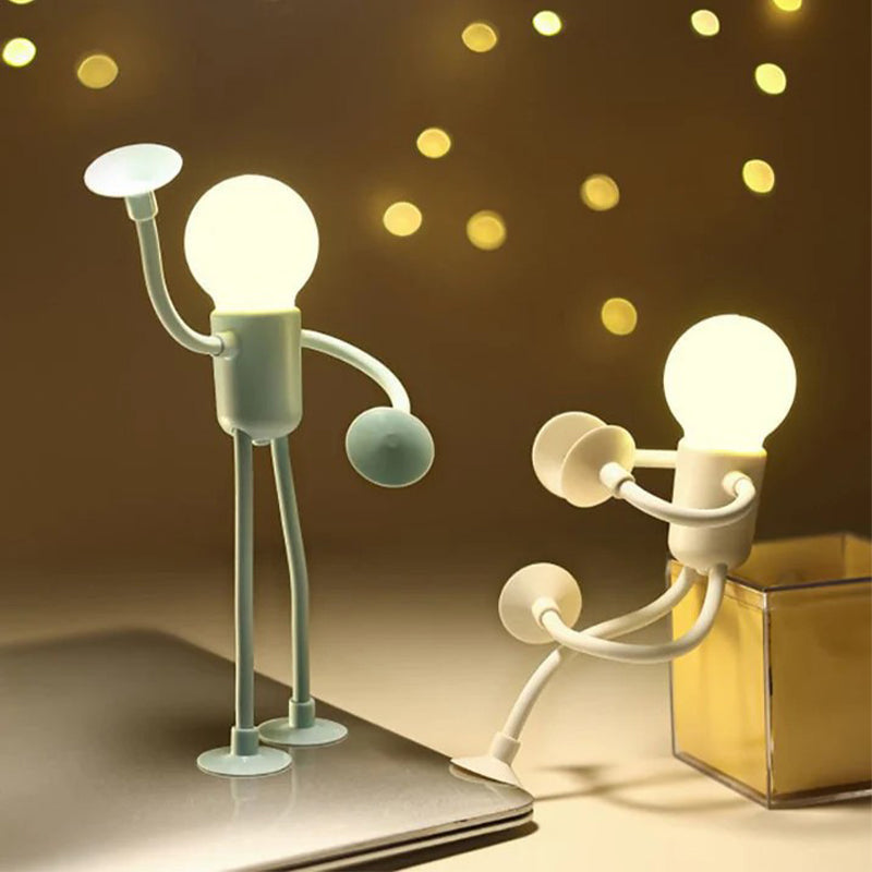 Two lit figure lamps on a desk, one on a laptop and one on a clear box.