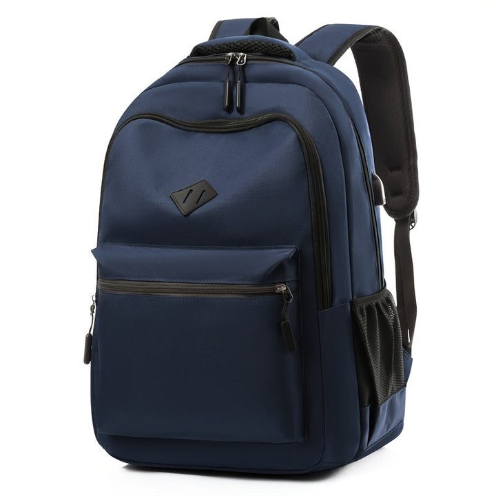Navy blue backpack seen from the front at an angle, with a zippered front pocket, a mesh side pocket and padded shoulder straps. 5