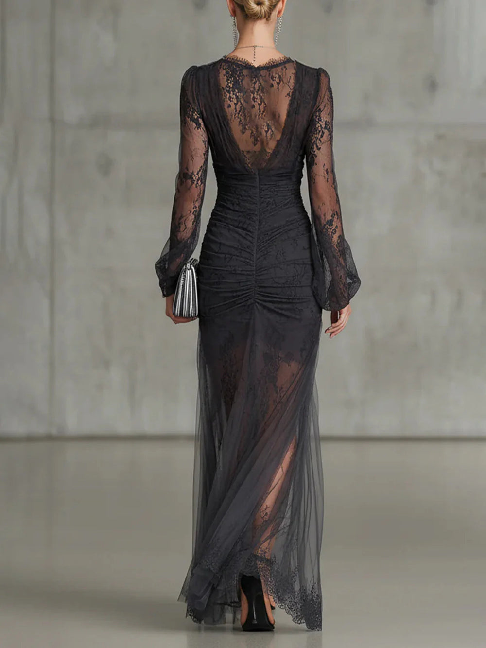 Black lace gown back view with a sheer lace back, ruched center seam and flowing tulle hem.