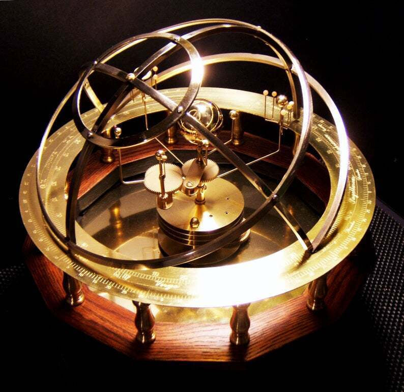 Another view of a smaller brass orrery with armillary rings, gear mechanism and a round wooden base.
