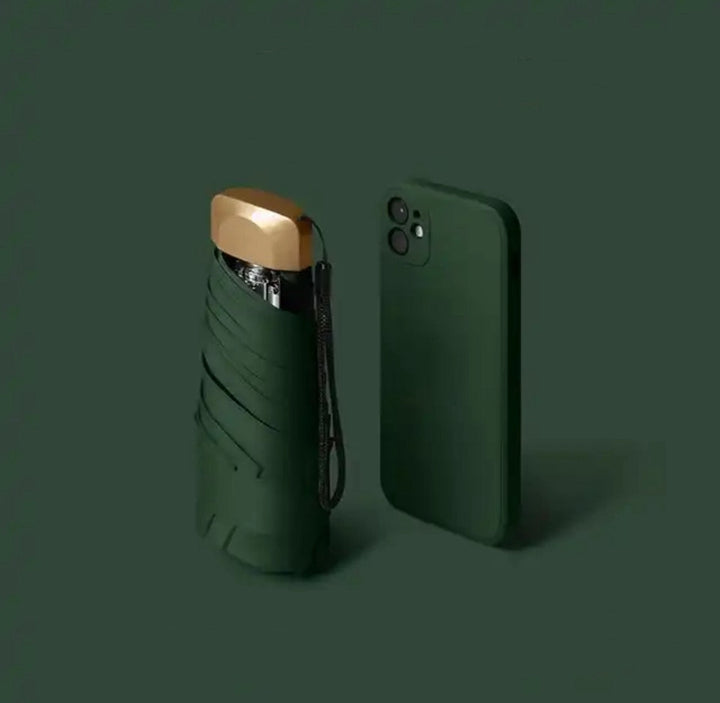 Folded green umbrella with a gold cap and wrist strap next to a green smartphone.
