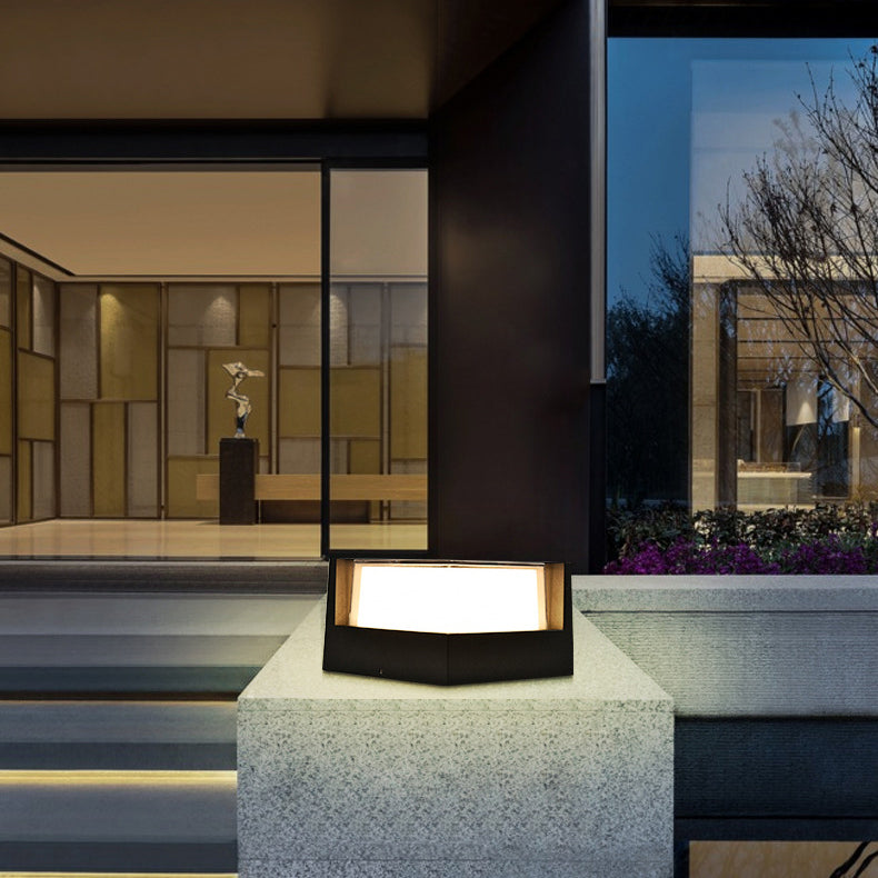 Angular black lamp with a lit diffuser on a concrete pillar outside a modern building entrance with glass walls. 3