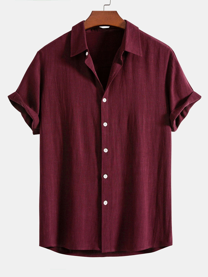 Burgundy short sleeve shirt on a wooden hanger, front view with white buttons and cuffed sleeves.