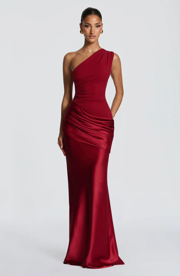 Front view of the red satin maxi dress with one hand resting in a pocket, showing the draped waist and long skirt. 24