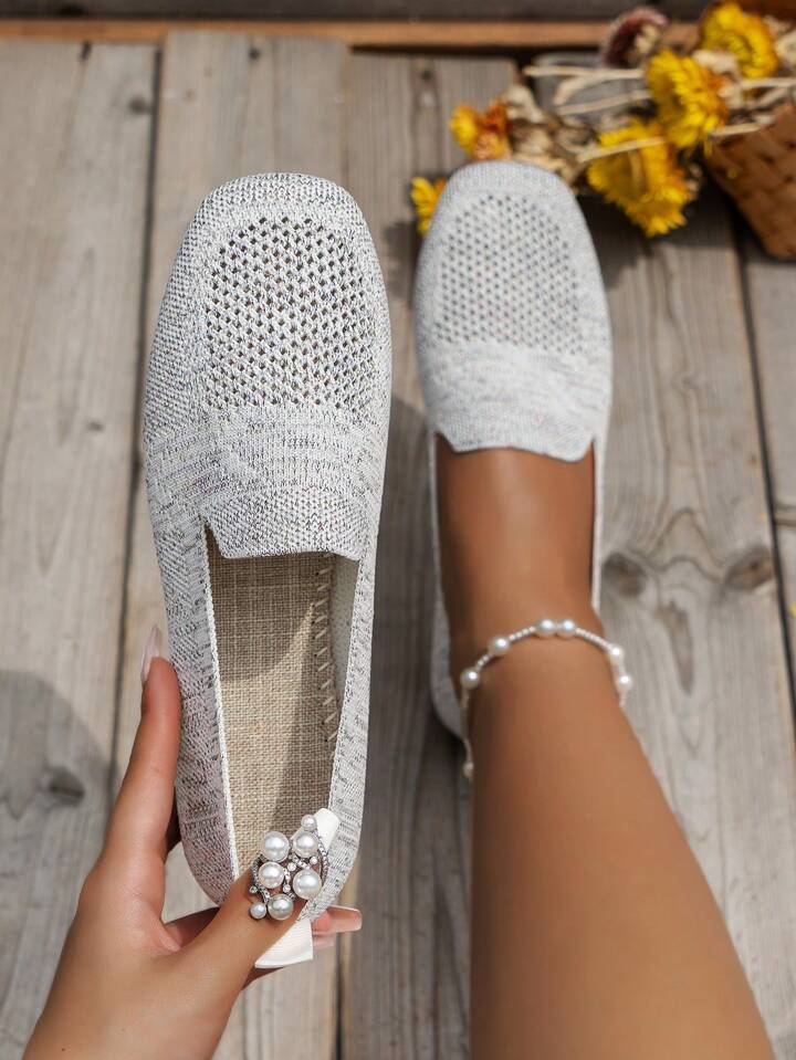 Top view of light gray mesh-toe knit flats with a woven beige insole.