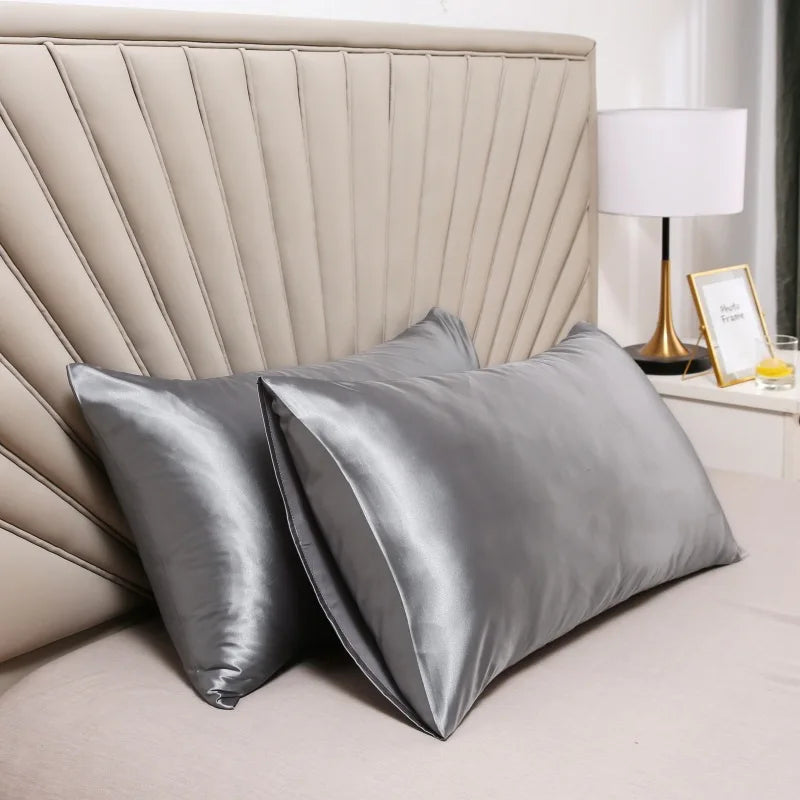Gray silk pillowcases in a bedroom, shown propped against a headboard.