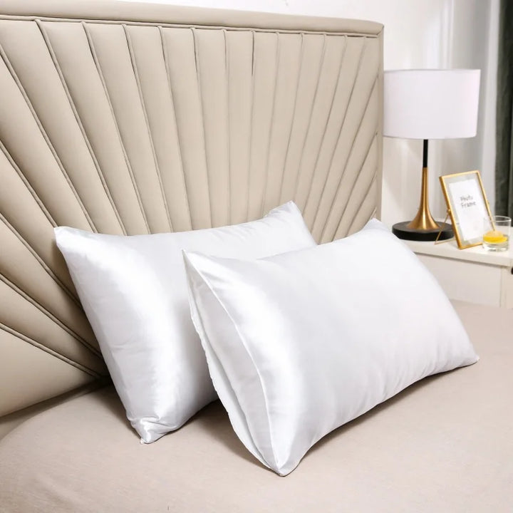 White silk pillowcases in a bedroom, shown propped against a headboard.