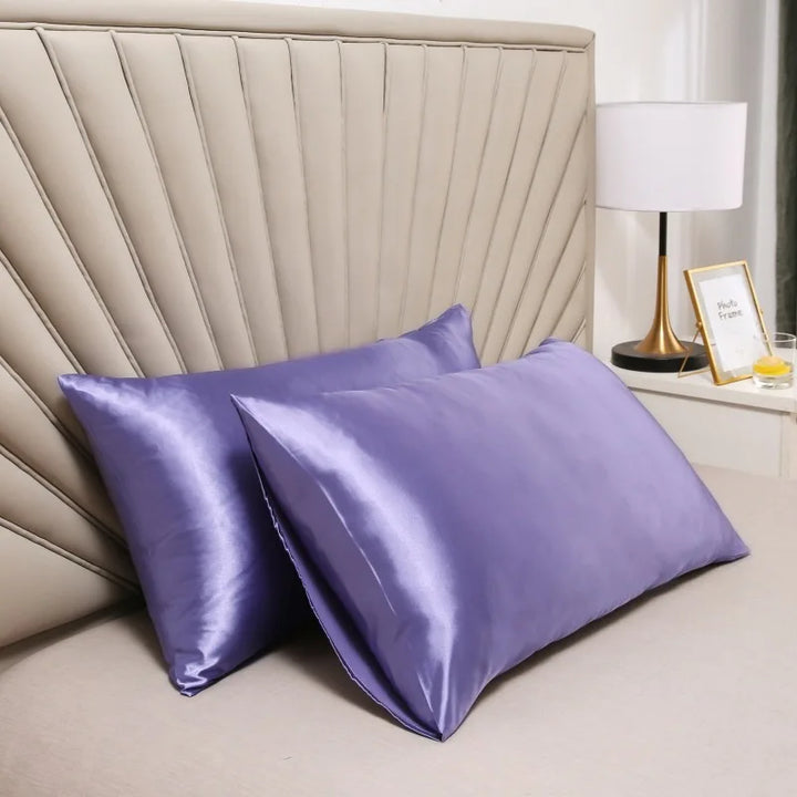 Pair of lavender purple glossy pillowcases resting against a fan-pleated headboard next to a bedside lamp. 4