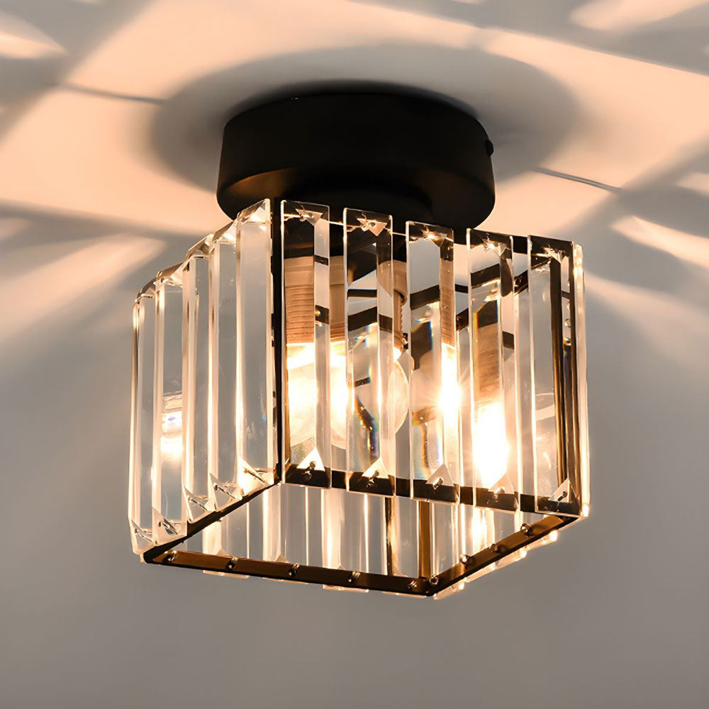 Black square ceiling light detail with clear crystal panels and warm bulbs glowing inside.