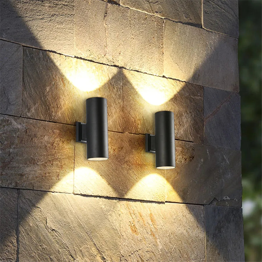 Black LED outdoor wall light, another view, with warm up and down light on a stone block wall.