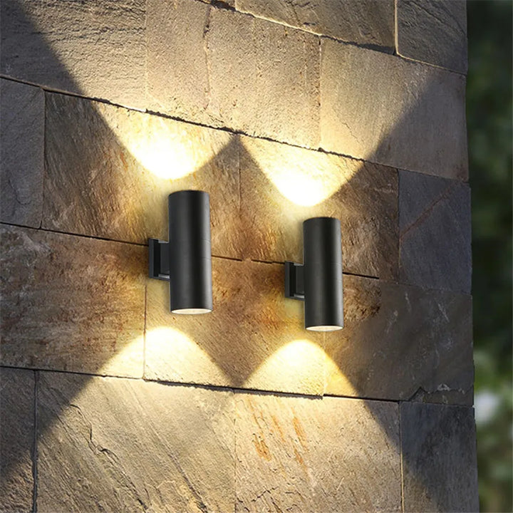 Black LED outdoor wall light, another view, with warm up and down light on a stone block wall.