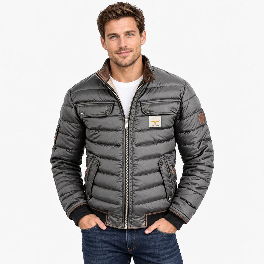 Man wearing the gray quilted jacket zipped up over a white tee, hands in jeans pockets 10
