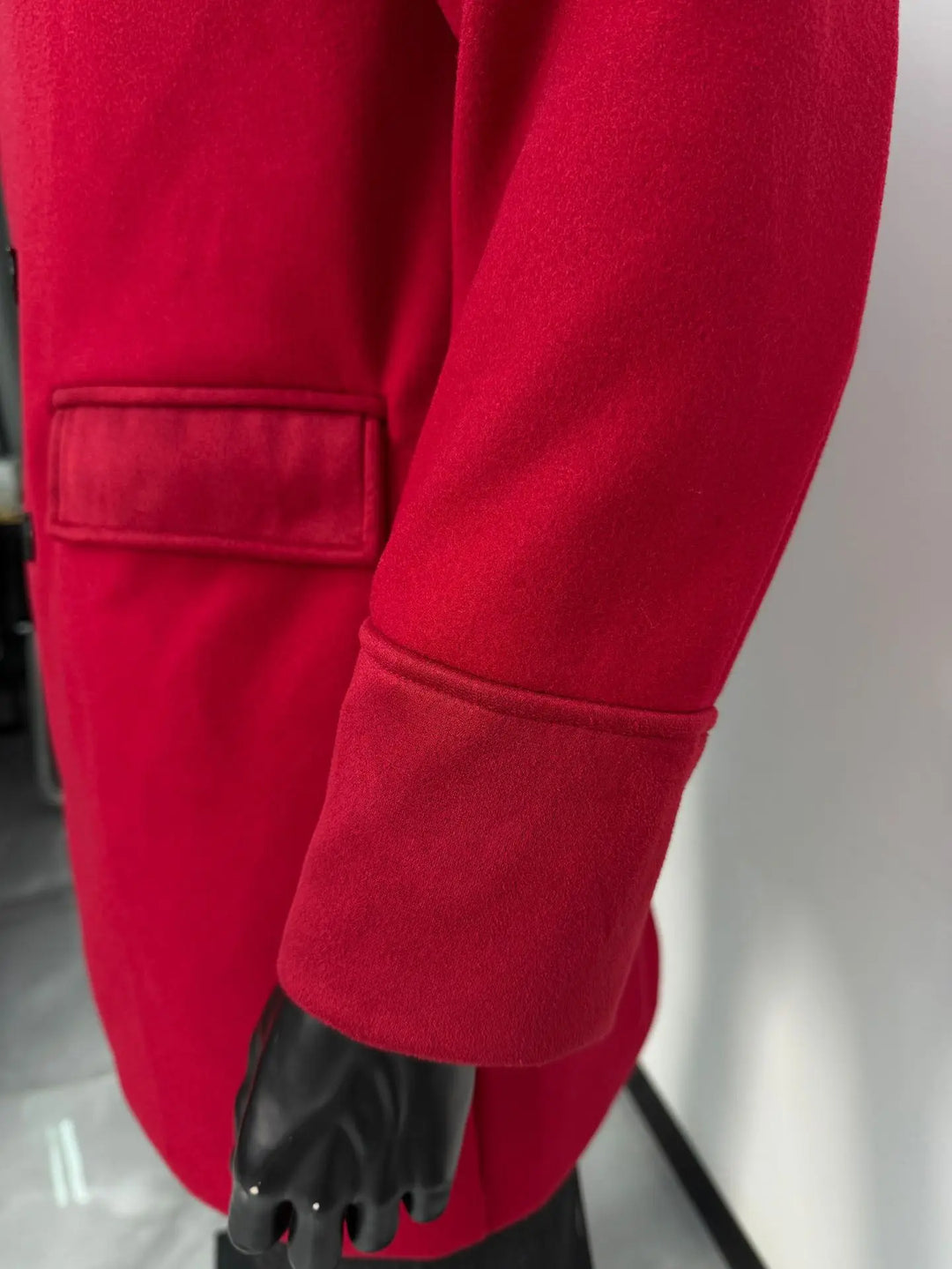 Close-up of the red coat's flap pocket and wide cuff with a soft suede-like finish 10