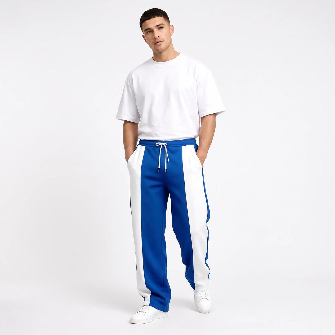 Model in royal blue and white paneled sweatpants with white tee, hands in pockets 10