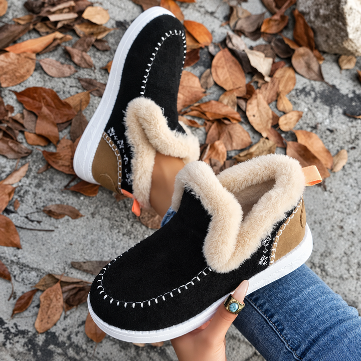 Close-up from above of black slip-ons with tan heel panel, snowflake embroidery and orange heel pull tab 7