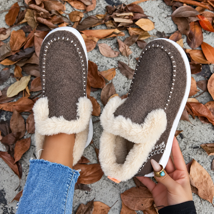 Top-down view of brown slip-ons with white stitching, one held open to show the soft plush lining 8