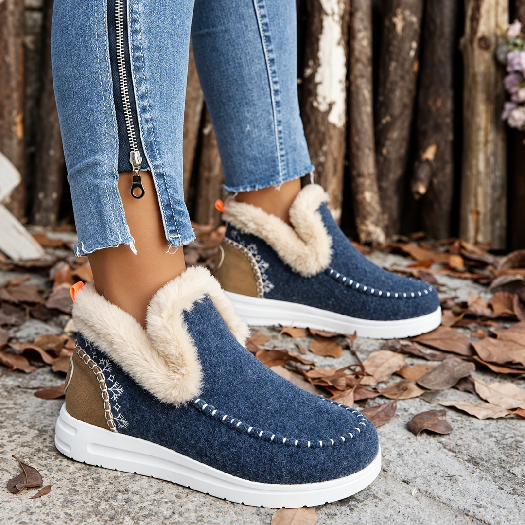 Navy blue slip-ons with cream plush collar, tan heel panel and orange pull tab, worn with zippered jeans 10