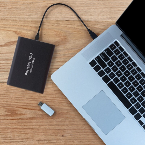 Black portable drive another view connected to an open laptop on a desk.