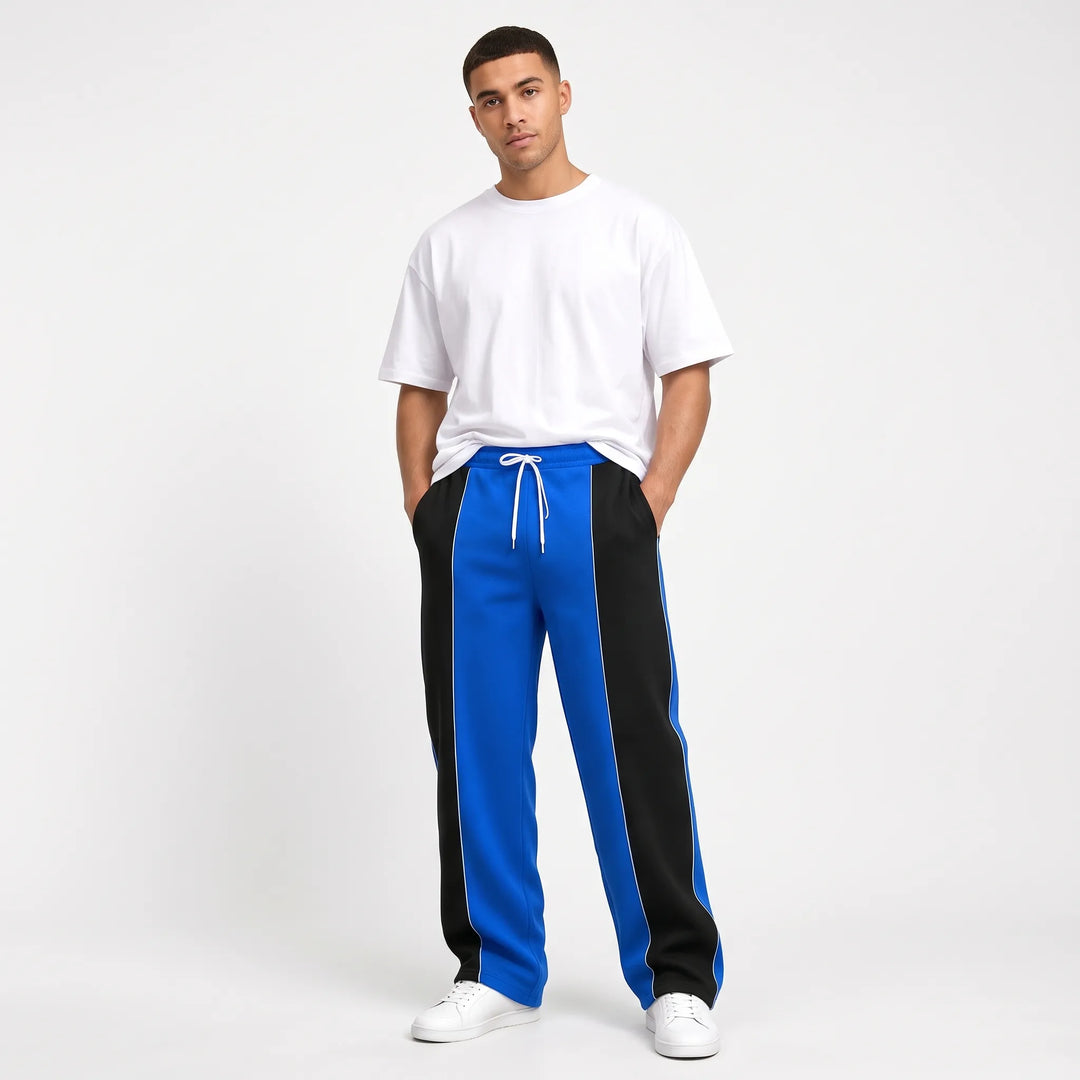Model in bright blue and black paneled sweatpants with thin white piping along the seams 11