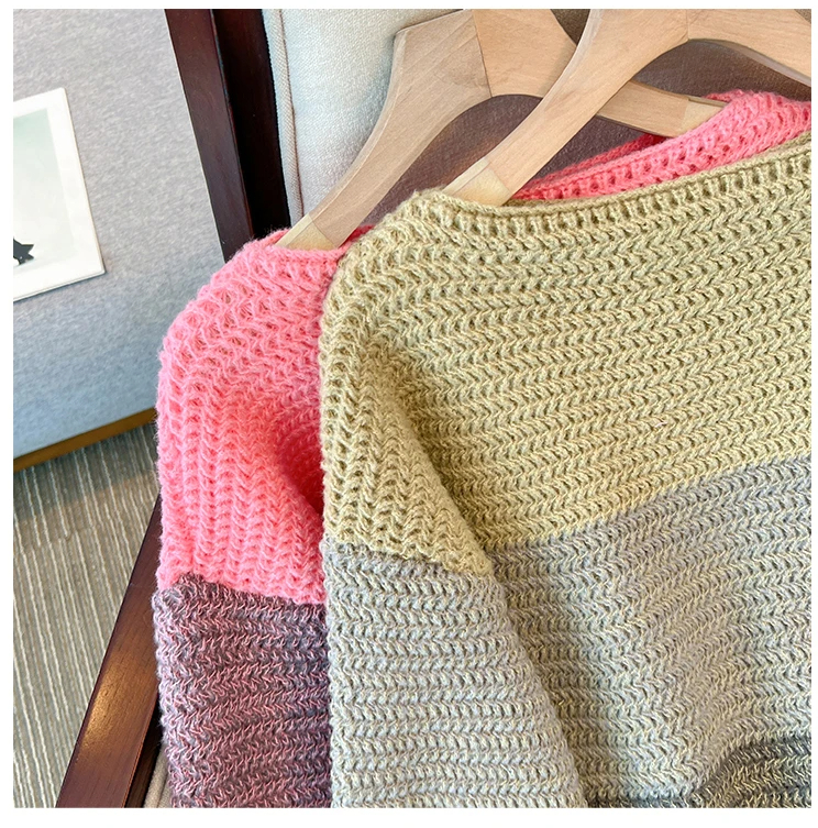 Zwei gestrickte Pullover, rosa und beige, auf Holzkleiderbügeln, gemütliche Wintermode.