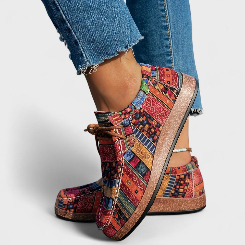 Side and heel detail of red, orange and blue patterned lace-up sneakers with thick cork-style soles.