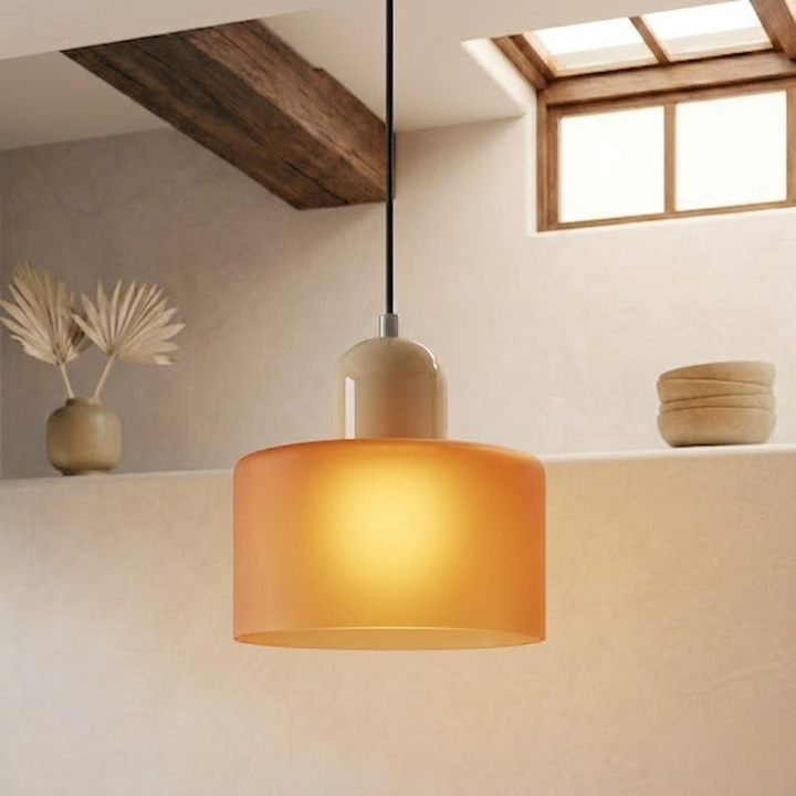 Lit frosted orange drum shade with a beige cap, glowing warmly while hanging from a black cord. 18