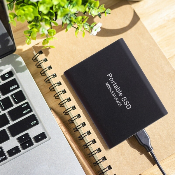 Black portable drive another view connected to a laptop on a notebook.