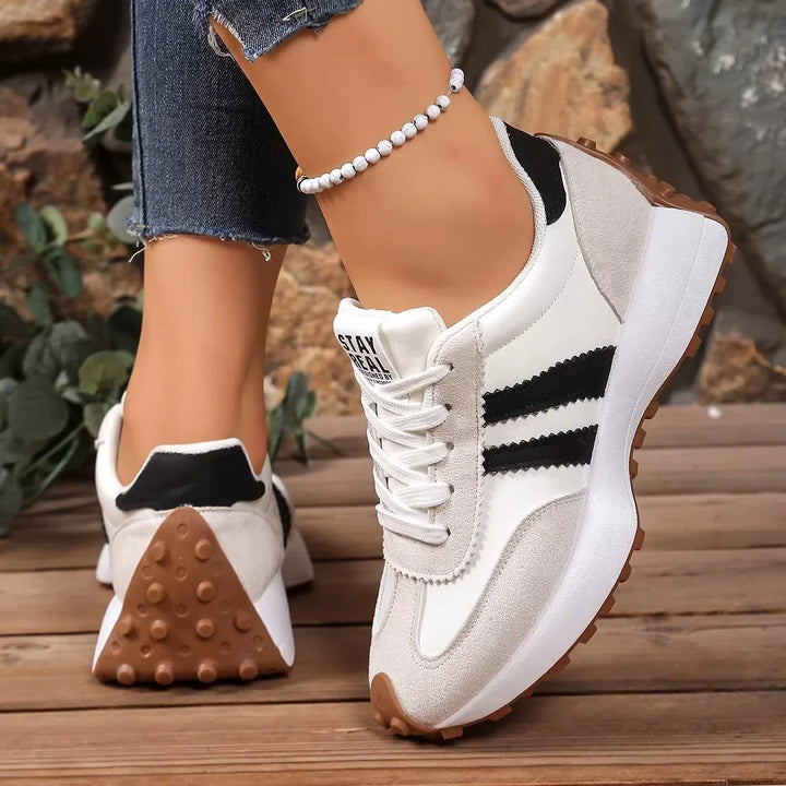 Back and side view of cream trainers with black stripes, showing the studded gum-colored heel sole 12