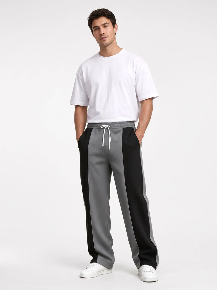 Model in gray and black paneled sweatpants with a soft smooth finish, white tee and sneakers 13
