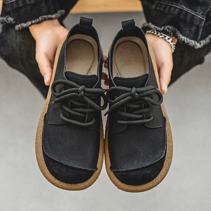 Pair of black lace-up shoes held in two hands, showing insoles and toe caps 13