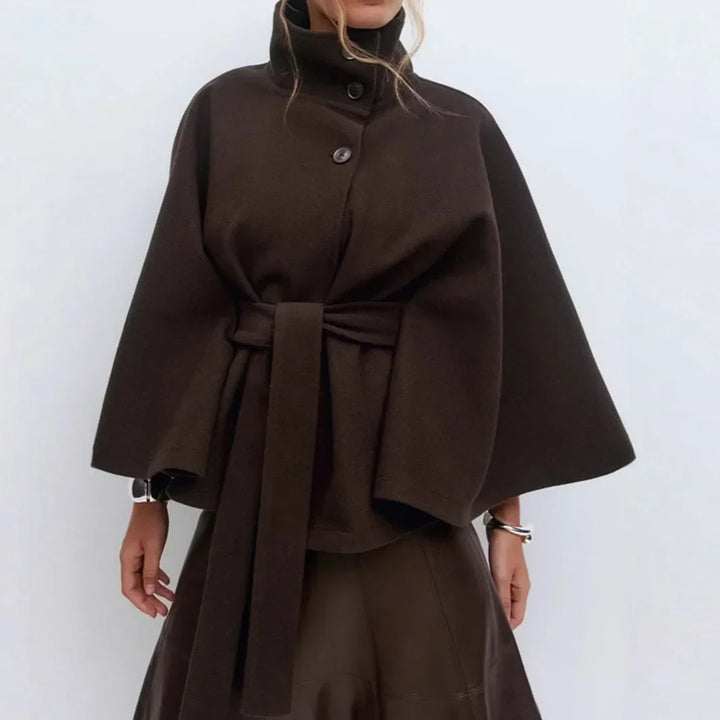 Dark brown cape jacket with a wide belt tied at the waist, worn with silver bracelets 13