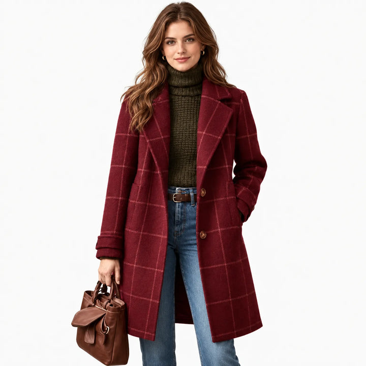 Model with wavy brown hair wearing the burgundy checked coat on a white background, holding a leather tote 13