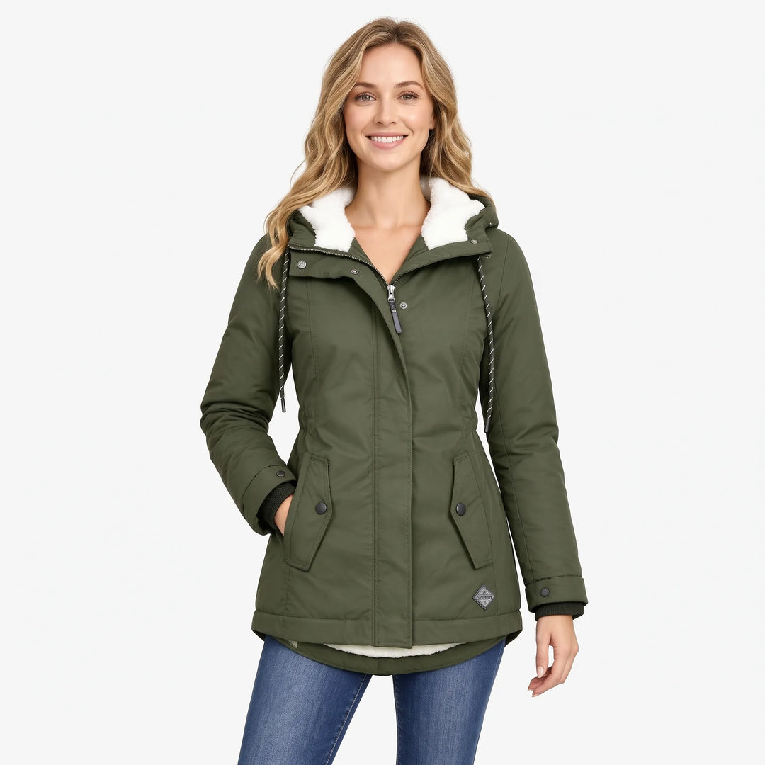 Smiling model wears the olive green jacket with its curved hem, fleece hood and drawcords over jeans 14