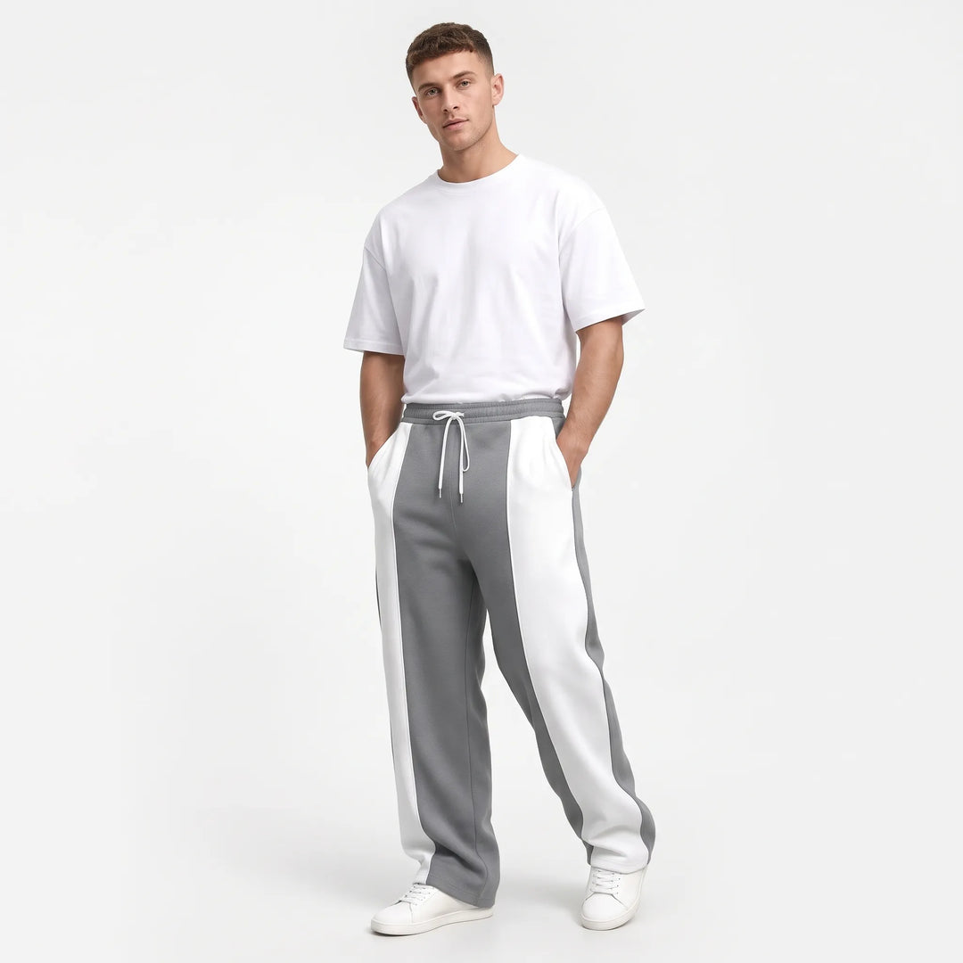 Model in gray and white paneled sweatpants with white drawstring, tee and sneakers 14