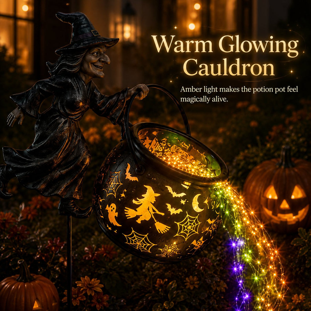 Close-up of the cauldron lit from within in amber with witch-on-broom and spiderweb cutouts and a bright light stream below.