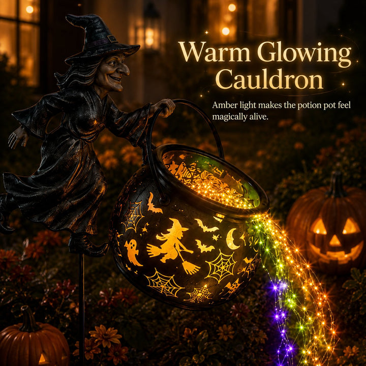 Close-up of the cauldron lit from within in amber with witch-on-broom and spiderweb cutouts and a bright light stream below.