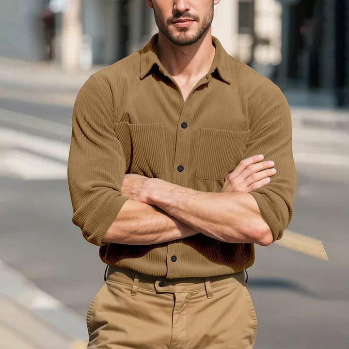 Model with arms crossed in the tan ribbed shirt, standing on a sunny city street 15