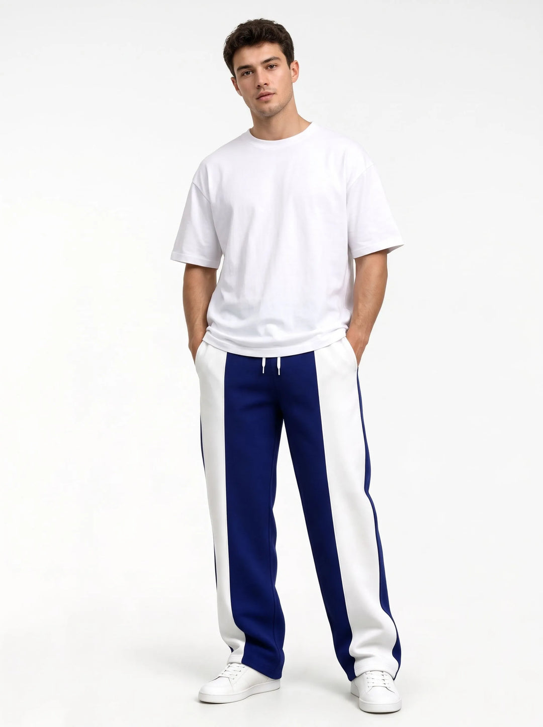 Model in deep blue and white paneled sweatpants, standing straight with hands in pockets 15