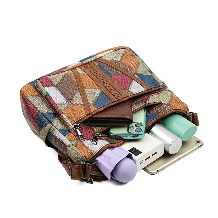 Bag lying open with a wallet, phone, power bank, water bottle, tablet and folded umbrella tucked into its pockets and compartments. 14