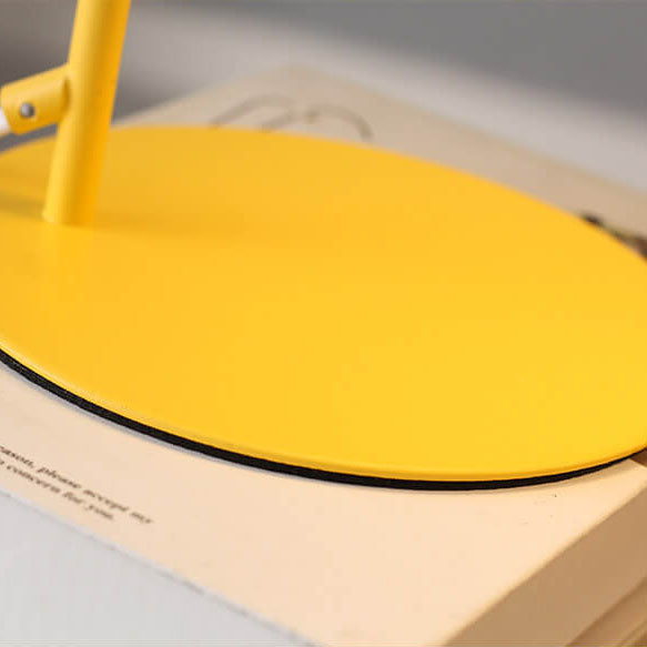 Detail of the round, flat yellow base and the lower end of the stem, resting on a book 4