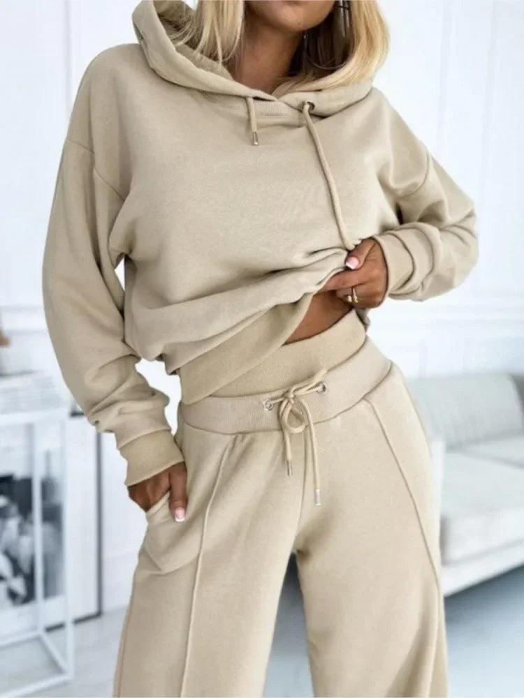 Close-up of a model in a beige hoodie and drawstring pants, hand resting in the pocket 15