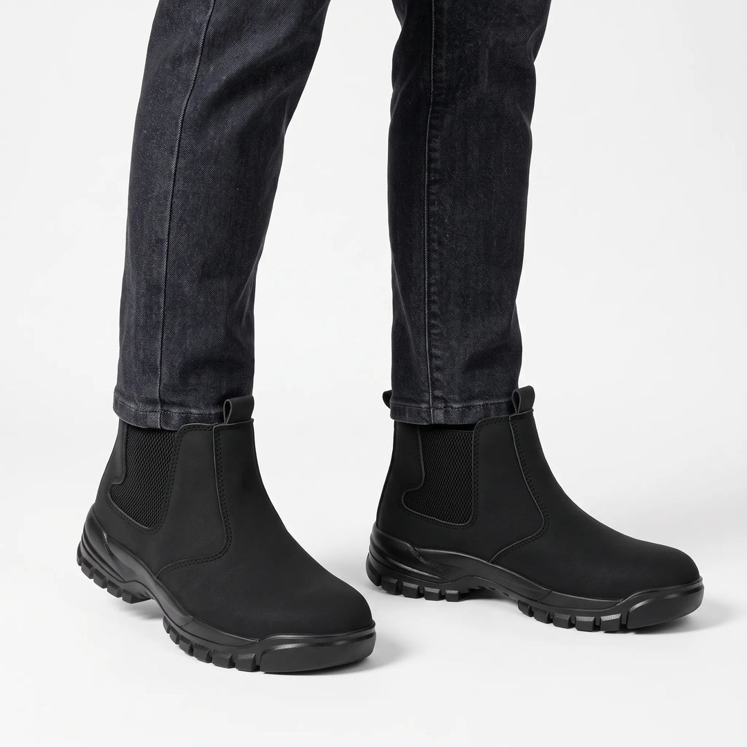Black boots worn with dark gray jeans against a plain white background 15