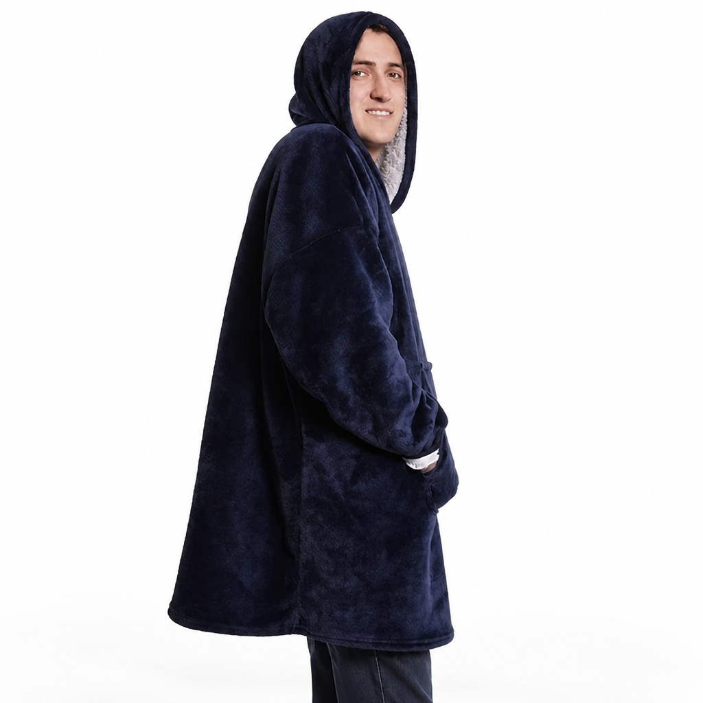 Man wearing the navy blue hoodie blanket with the hood up, smiling over his shoulder with one hand in the front pocket.