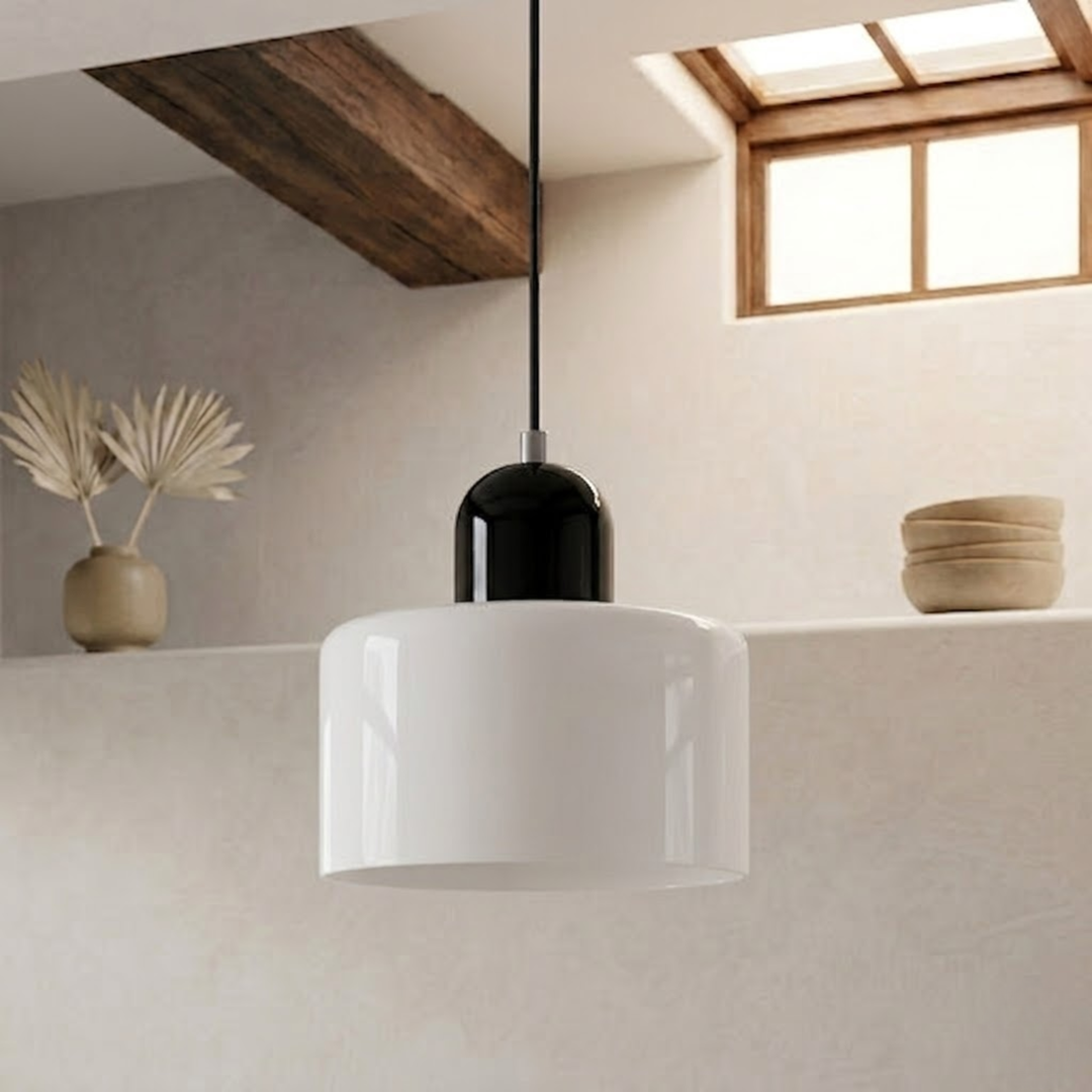 Glossy white drum shade with a black dome cap hangs on a black cord beside a wood beam and skylight. 22