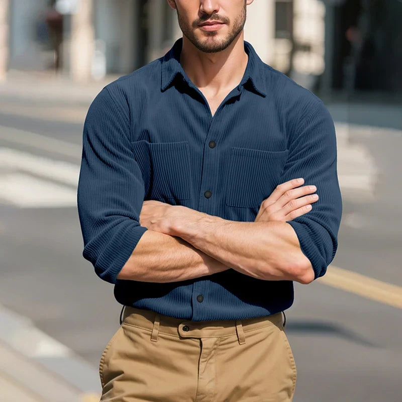Model with arms crossed in the navy ribbed shirt, standing on a sunny city street 16