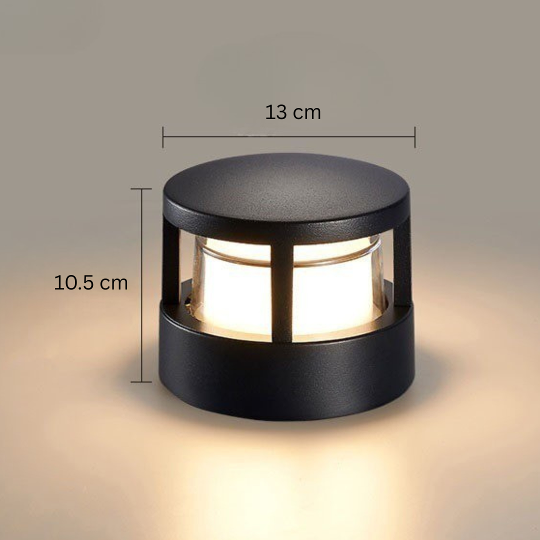 Round flat-cap black lamp with dimension lines marking its width and height, glowing warm white on a beige backdrop. 14