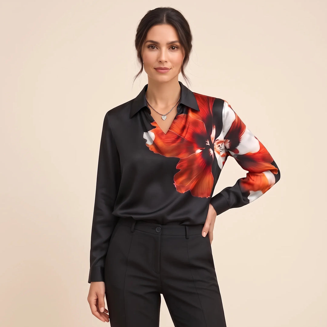 Studio view of the black blouse with bold red and white flower print across one shoulder and sleeve 16
