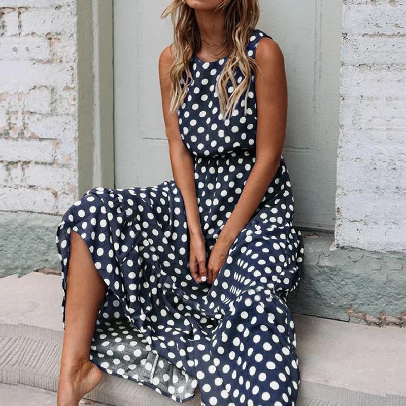 Woman seated against a brick wall wearing the navy blue polka dot version with a gathered waist 5