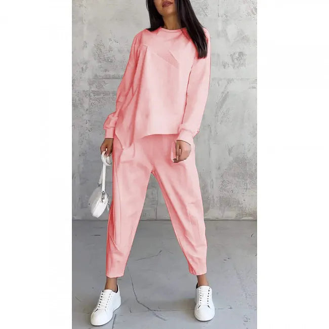 Woman in the soft coral pink set on a plain white background, with white sneakers and a white bag.